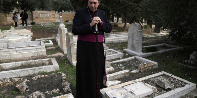 Hosam Naoum, a Palestinian Anglican bishop, pauses where vandals desecrated more than 30 graves at a historic Protestant Cemetery on Jerusalem's Mount Zion in Jerusalem, Wednesday, Jan. 4, 2023. Israel's foreign ministry called the attack an "immoral act" and "an affront to religion." Police officers were sent to investigate the profanation.  