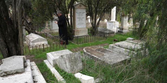 4 Ocak 2023 Çarşamba, Kudüs'ün Eski Şehri'ndeki Kudüs'ün Zion Dağı'ndaki tarihi bir Protestan mezarlığında vandallar 30'dan fazla mezara saygısızlık ederken bir mezar taşı düşüyor.