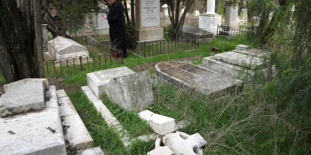 A tombstone falls as vandals desecrate more than 30 graves at a historic Protestant cemetery on Jerusalem's Mount Zion in the Old City of Jerusalem, Wednesday, January 4, 2023.