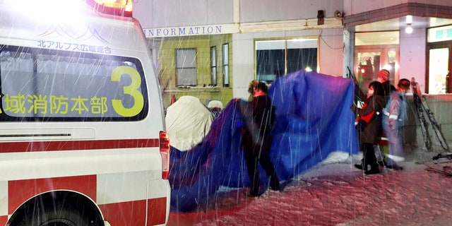 Injured skiers, behind a blue sheet, get into an ambulance at a ski resort in the village of Otari, Nagano prefecture, Japan on Sunday.