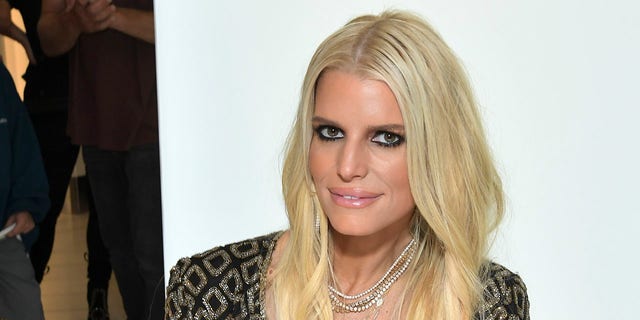 Jessica Simpson soft smiles and looks slightly up at an event at The Grove
