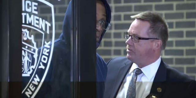 Lashawn Mackey, left, quickly ducks his head down while being lead out of the police precinct following his arrest for Maria Hernandez's murder. 