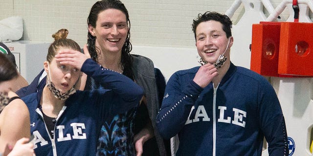 La nadadora de la Universidad de Pensilvania Lia Thomas (centro) sonríe con el nadador de la Universidad de Yale Iszac Henig (derecha) después de ganar el estilo libre de 100 yardas en la Liga Femenina de Natación y Buceo Ivy 2022 en Blodgett Pool el 19 de febrero de 2022 en Cambridge, Massachusetts.