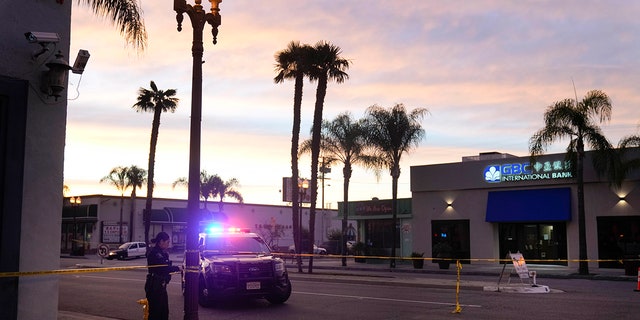 Un oficial de policía ata cinta alrededor de un poste de luz en Monterey Park, California, el domingo 22 de enero de 2023. Se produjo un tiroteo masivo en un club de baile después de la celebración del Año Nuevo Lunar, lo que provocó una búsqueda del sospechoso. 