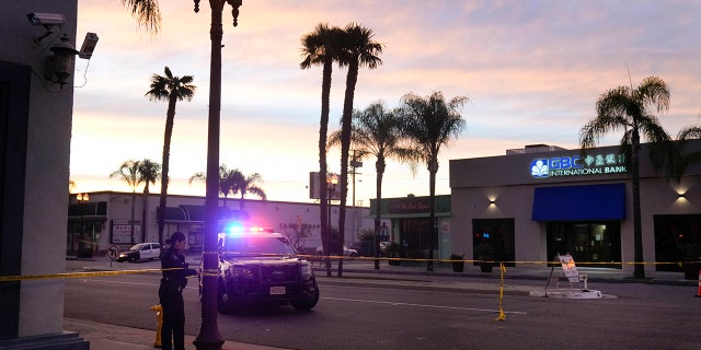 A police officer ties tape around a light pole in Monterey Park, Calif., Sunday, Jan. 22, 2023. A mass shooting took place at a dance club following a Lunar New Year celebration, setting off a manhunt for the suspect. 