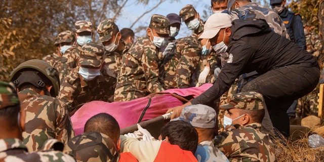 Rescue workers recover the body of a victim of a passenger plane that crashed in Pokhara, Nepal, Sunday, Jan. 15, 2023. A plane making a 27-minute flight to a Nepal tourist town crashed into a gorge Sunday while attempting to land at a newly opened airport, killing at least 68 of the 72 people aboard. At least one witness reported hearing cries for help from within the fiery wreck, the country’s deadliest airplane accident in three decades.