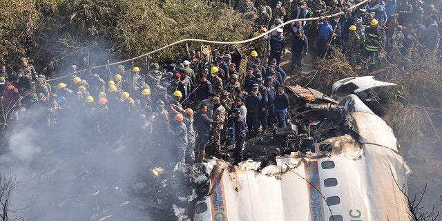 Petugas penyelamat Nepal dan warga sipil berkumpul di sekitar reruntuhan pesawat penumpang yang jatuh di Pokhara, Nepal, pada Minggu, 15 Januari 2023.
