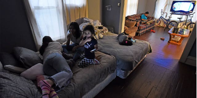 A mother and children use devices while on the couch.