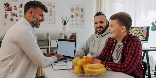 Doctor explaining how to lose weight to a teenager and his father.