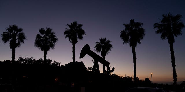 A pump jack sits in front of palm trees on June 9, 2021, in Signal Hill, California.