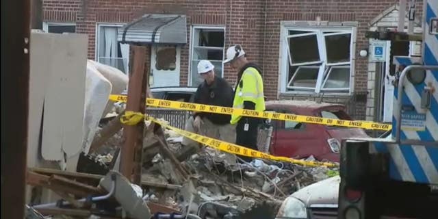 Officials observe the wreckage following a suspected gas explosion.