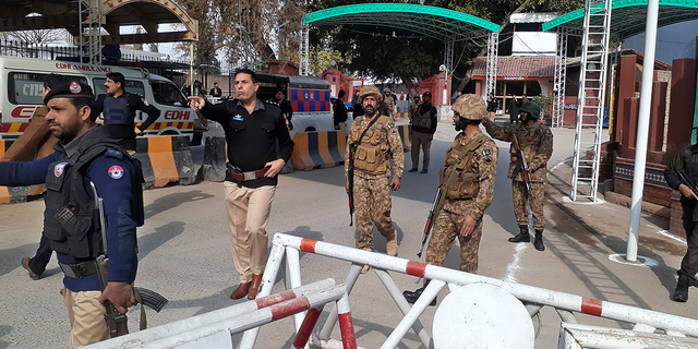 Army soldiers and police officers clear the way for ambulances rushing toward a bomb explosion site.