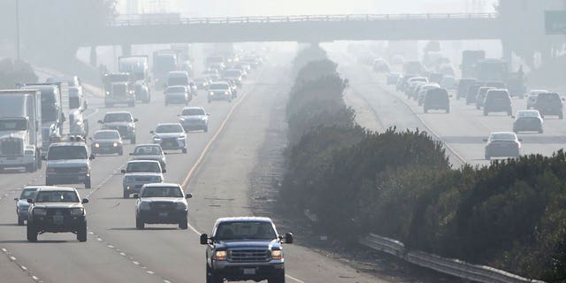 California has some of the worst soot-polluted cities in the nation. Pictured: Cars drive through a foggy atmosphere in Fresno, California, on Dec. 28, 2017.