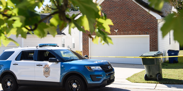 A police officer parks in front of the home of a suspect of a shooting that left five people dead and two others injured Oct. 14, 2022, in Raleigh, N.C.