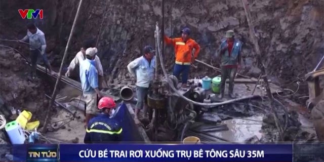 Keli gelbėtojai ir statybininkai kasa aplink betoninį stulpą, kad išgelbėtų berniuką.