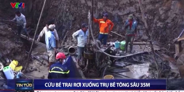 Various rescuers and construction workers dig around concrete hole to save boy.