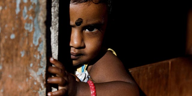 Een kind kijkt uit vanuit zijn huis in Bogawantalawa, Sri Lanka, op 29 april 2022.