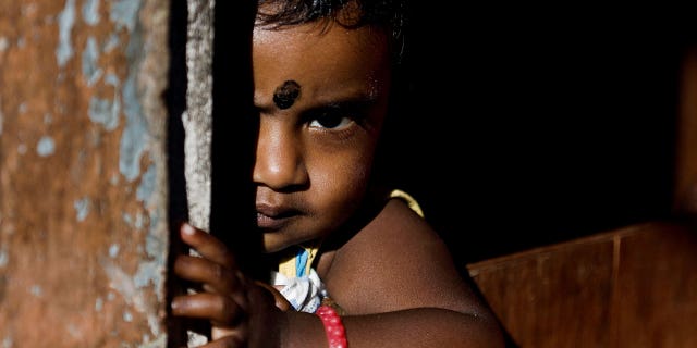 Een kind kijkt uit vanuit zijn huis in Bogawantalawa, Sri Lanka, op 29 april 2022.