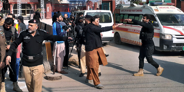 Police officers clear the way for ambulances leaving after carrying wounding people from bomb explosion site.