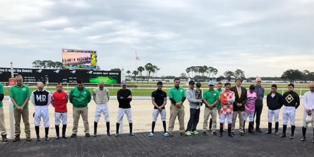 Jockeys and their valets observe a moment of silence in honor of 19-year-old exercise rider Daniel Quintero, who died this morning in a training accident.