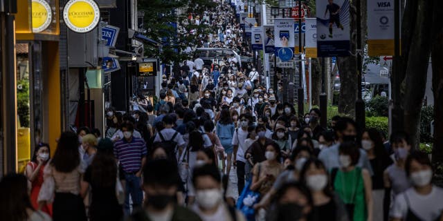 People walk on a busy shopping street in Tokyo on July 24, 2021.