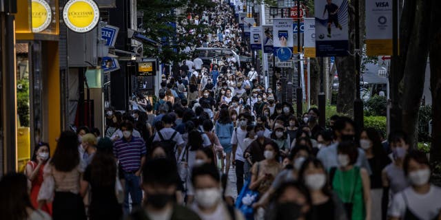 People walk along a crowded shopping street on July 24, 2021, in Tokyo.