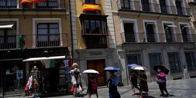 Tourists shelter under umbrellas during a heatwave in Toledo, Spain, on June 28, 2019. 
