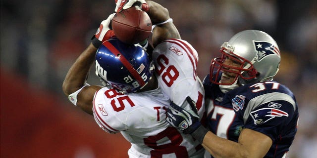 El receptor abierto de los New York Giants, David Tyree, clava el balón en su casco cuando atrapa un pase de 32 yardas al final del último cuarto del Super Bowl XLII contra los New England Patriots en el New England Stadium. 'Universidad de Phoenix.