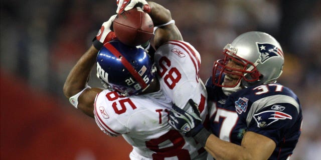 El receptor abierto de los New York Giants, David Tyree, clava el balón en su casco cuando atrapa un pase de 32 yardas al final del último cuarto del Super Bowl XLII contra los New England Patriots en el New England Stadium. 'Universidad de Phoenix.