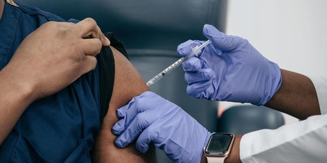 Lenox Hill Hospital Chair of Emergency Medicine Yves Duroseau receives the COVID-19 vaccine from Doctor Michelle Chester at Long Island Jewish Medical Center.