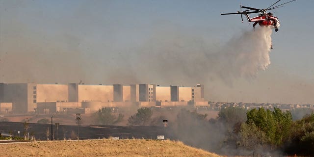 A helicopter drops water on flames from the Alturas Fire on May 12, 2022.