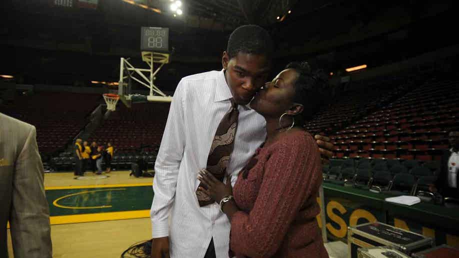 Texas basketball player Kevin Durant, left, walks with his mother, Wanda  Pratt, center and Texas coach