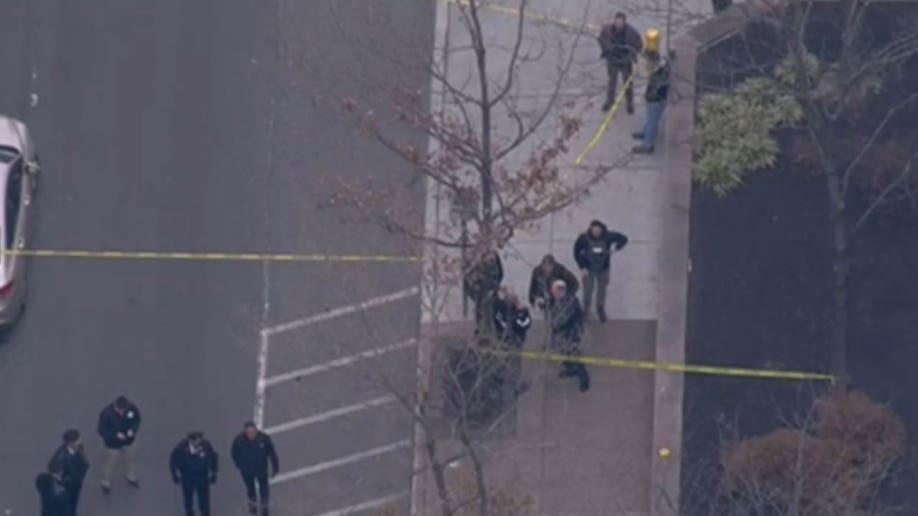 Law enforcement officers standing on the street next to caution tape.
