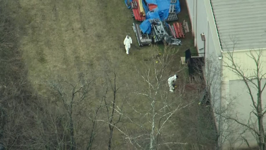 investigators searching for evidence behind warehouse