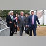 Three men wearing suits walk outside a courthouse.
