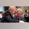 Two men look at documents inside a courtroom.
