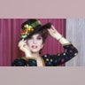 Gina Lollobrigida in a black hat with fruit on it and black shirt with colorful polka dots