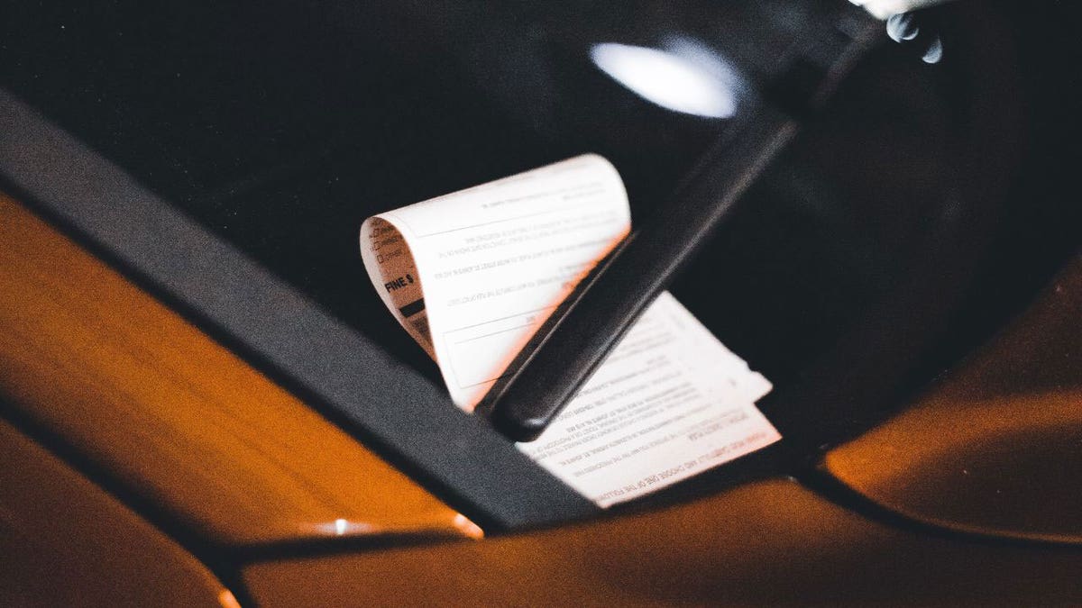 Photo of a parking ticket under a windshield wiper.