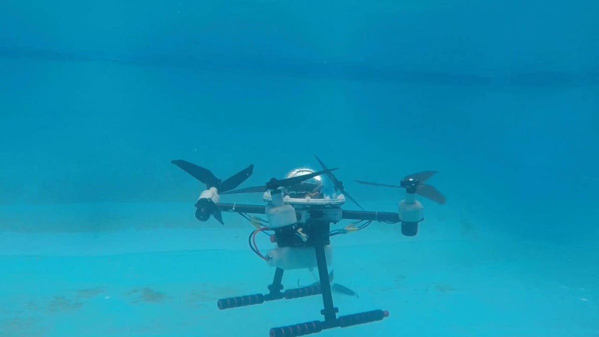 An underwater drone resting at the bottom of a pool.