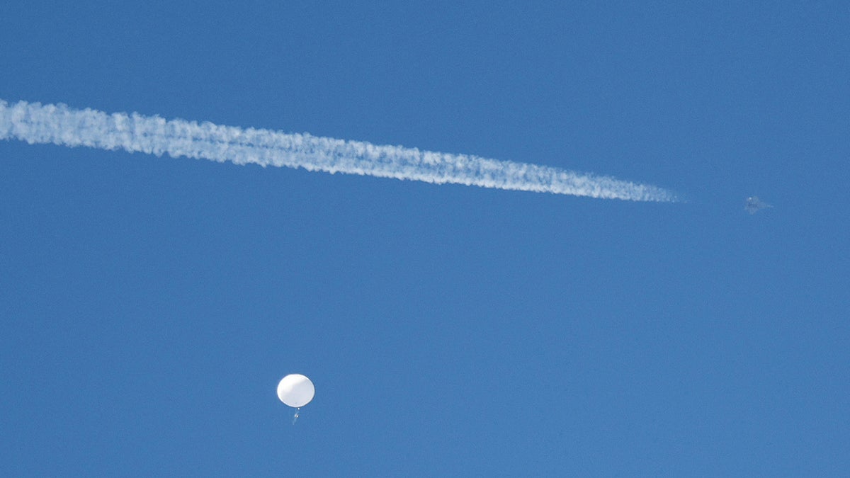 FILE PHOTO: A jet flies by a suspected Chinese spy balloon as it floats off the coast in Surfside Beach, South Carolina, U.S. February 4, 2023.  REUTERS/Randall Hill/File Photo