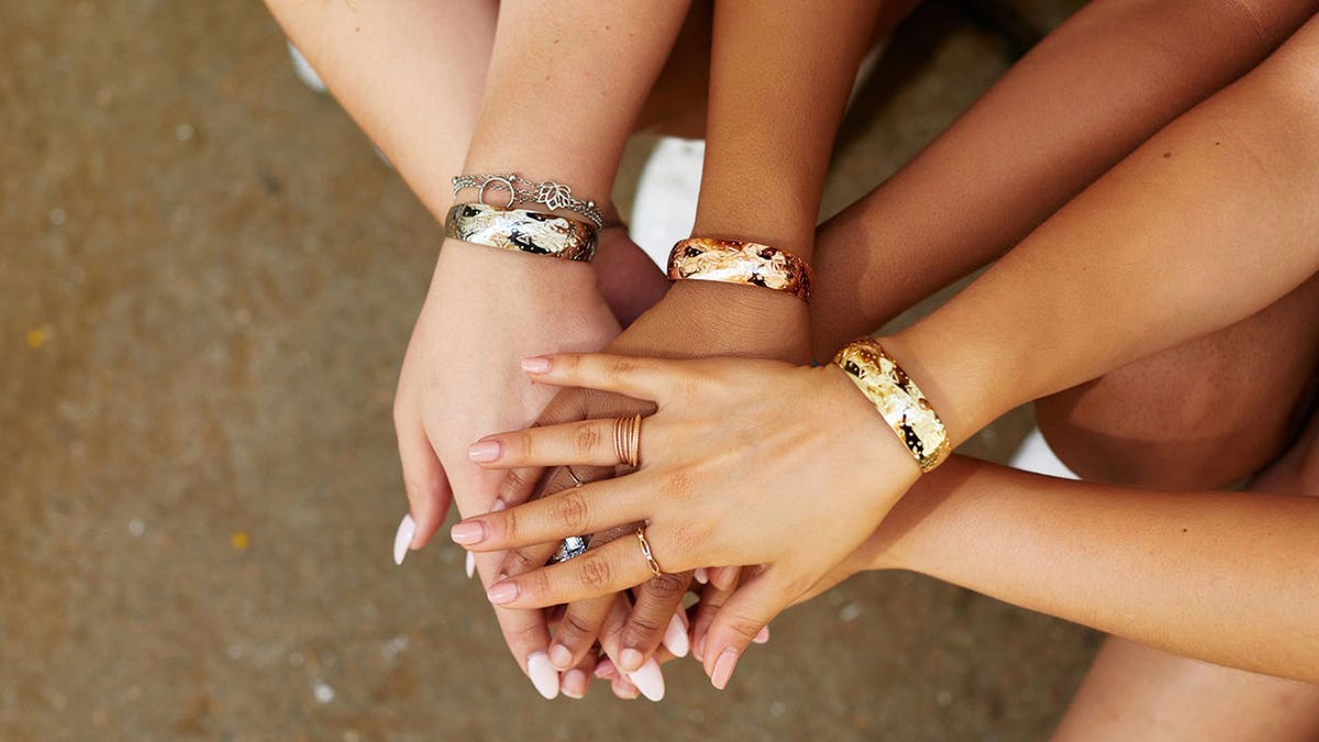 Women holding hands and showing their jewelry.