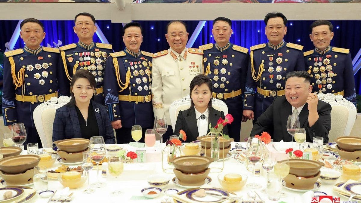 In this photo provided by the North Korean government, North Korean leader Kim Jong Un, front right, with his wife Ri Sol Ju, front left, and his daughter poses with military top officials for a photo at a feast to mark the 75th founding anniversary of the Korean People’s Army at an unspecified place in North Korea. 
