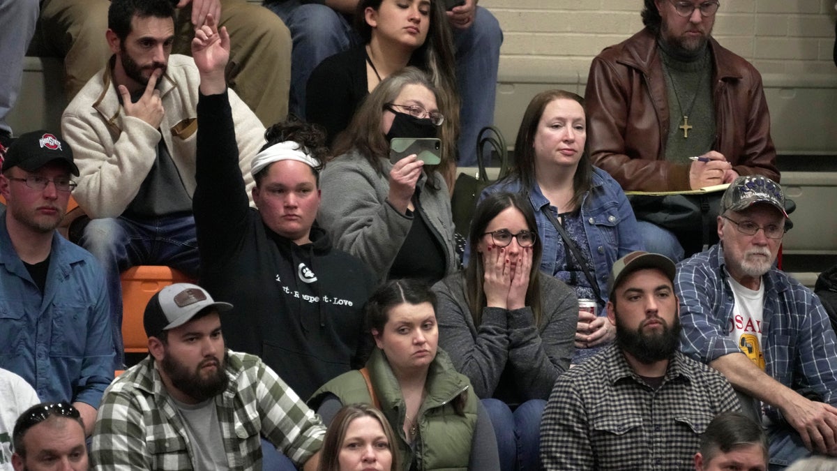 A woman raises her hand with a question during a town hall meeting at East Palestine High School in East Palestine, Ohio, Wednesday, Feb. 15, 2023. The meeting was held to answer questions about the ongoing cleanup from the derailment on Feb, 3, of a Norfolk Southern freight train carrying hazardous material. 