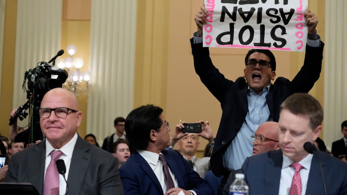 A protester interrupts H.R. McMaster, former national security adviser to President Donald Trump, as testifies during a hearing of a special House committee dedicated to countering China, on Capitol Hill, Tuesday, Feb. 28, 2023, in Washington. At right is Matthew Pottinger, former deputy national security adviser to President Donald Trump.(AP Photo/Alex Brandon)