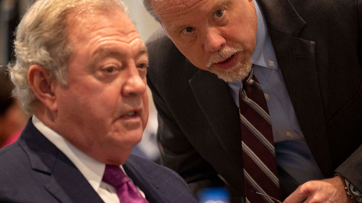 Two men speak inside a courtroom.