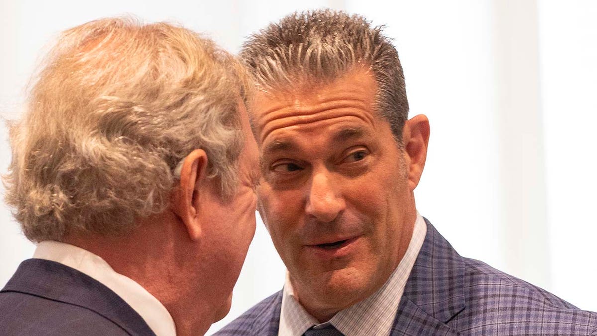 Two men speak inside a courtroom.