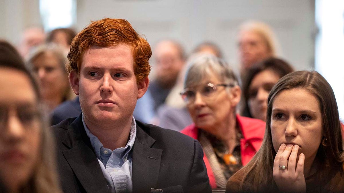 A man and women listen intently inside a courtroom.