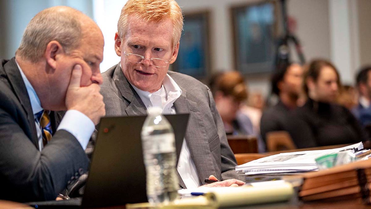 Two men speak inside a courtroom.