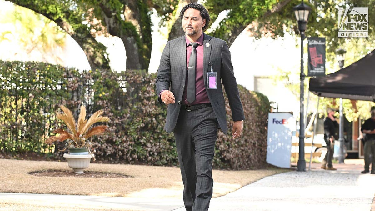 A man wearing a suit walks outside.