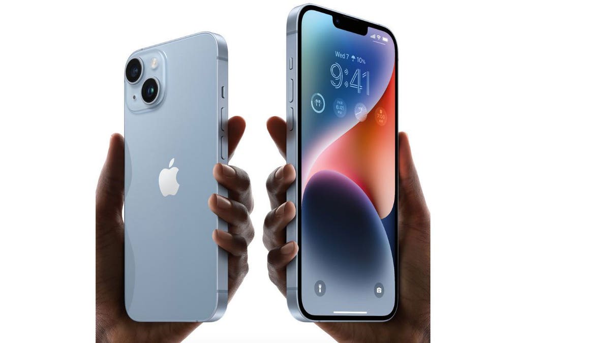 A person holding up two iPhones, one in each hand.